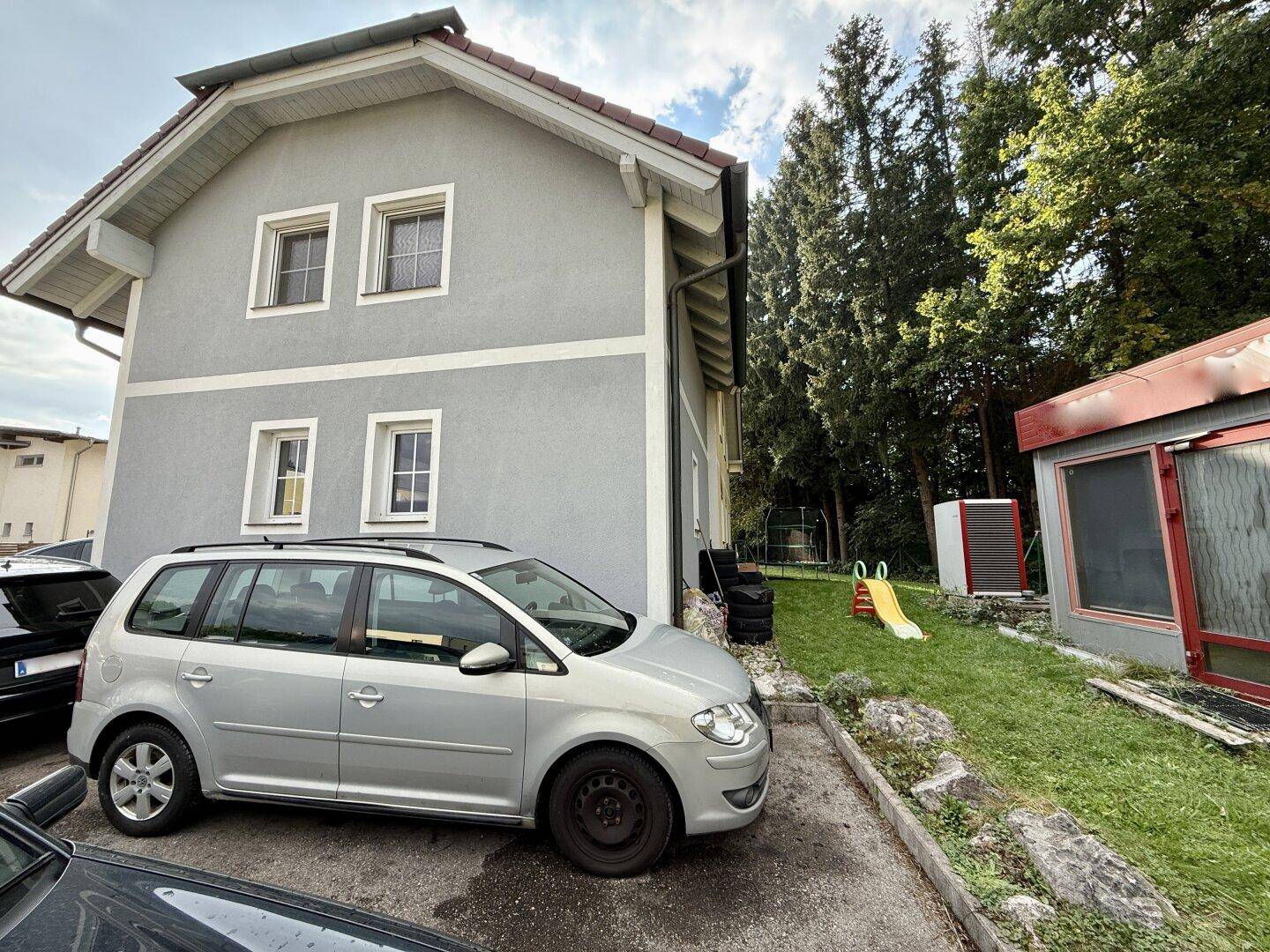 Hinterhofbereich mit Rasenfläche, Spielgeräten und angrenzendem Gebäude.