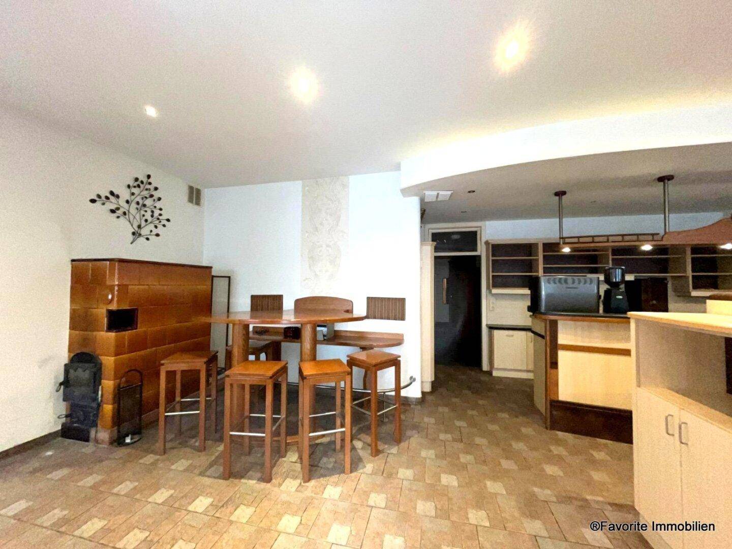 Gemütlicher Barbereich mit Kachelofen, Holztischen und gefliestem Boden, ideal für gesellige Runden und Entspannung.
