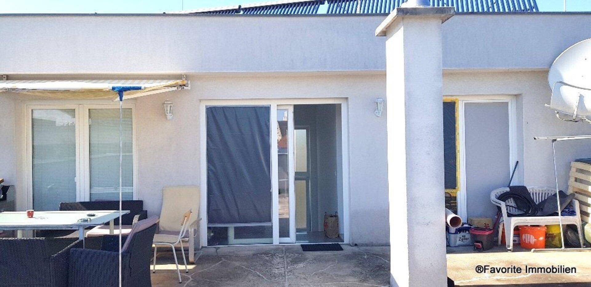 Dachterrasse mit Schiebetüren, Sonnenschutz und einigen Gartenmöbeln, die auf Nutzung warten.