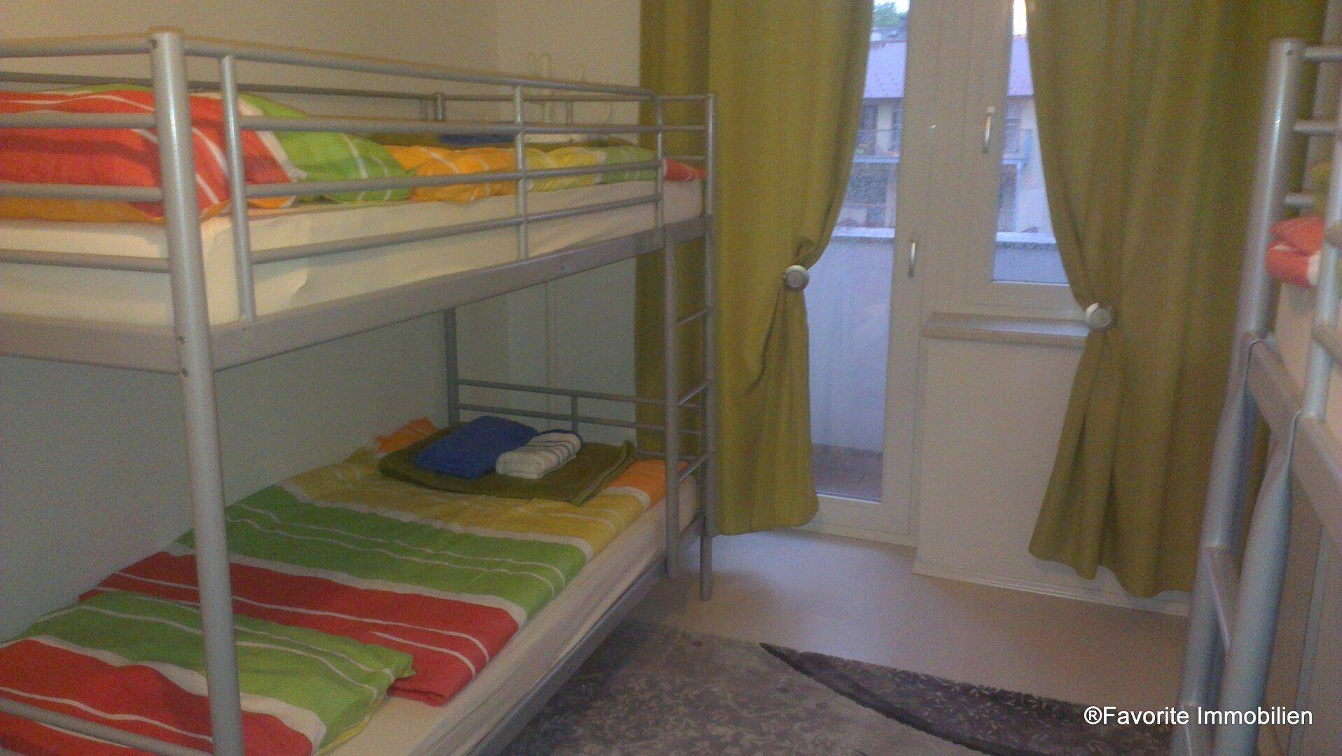 Schlafzimmer mit Etagenbetten und Zugang zu einem kleinen Balkon, ideal für Kinder oder Gäste.