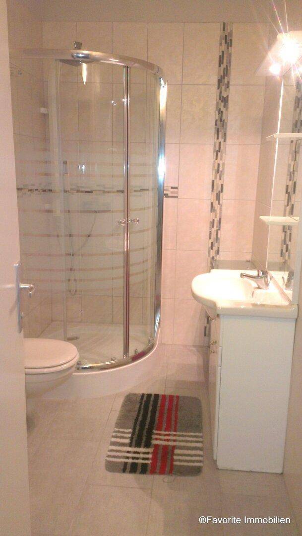 Modernes Badezimmer mit Duschkabine, Waschbecken und WC, ausgestattet mit hellen Fliesen.