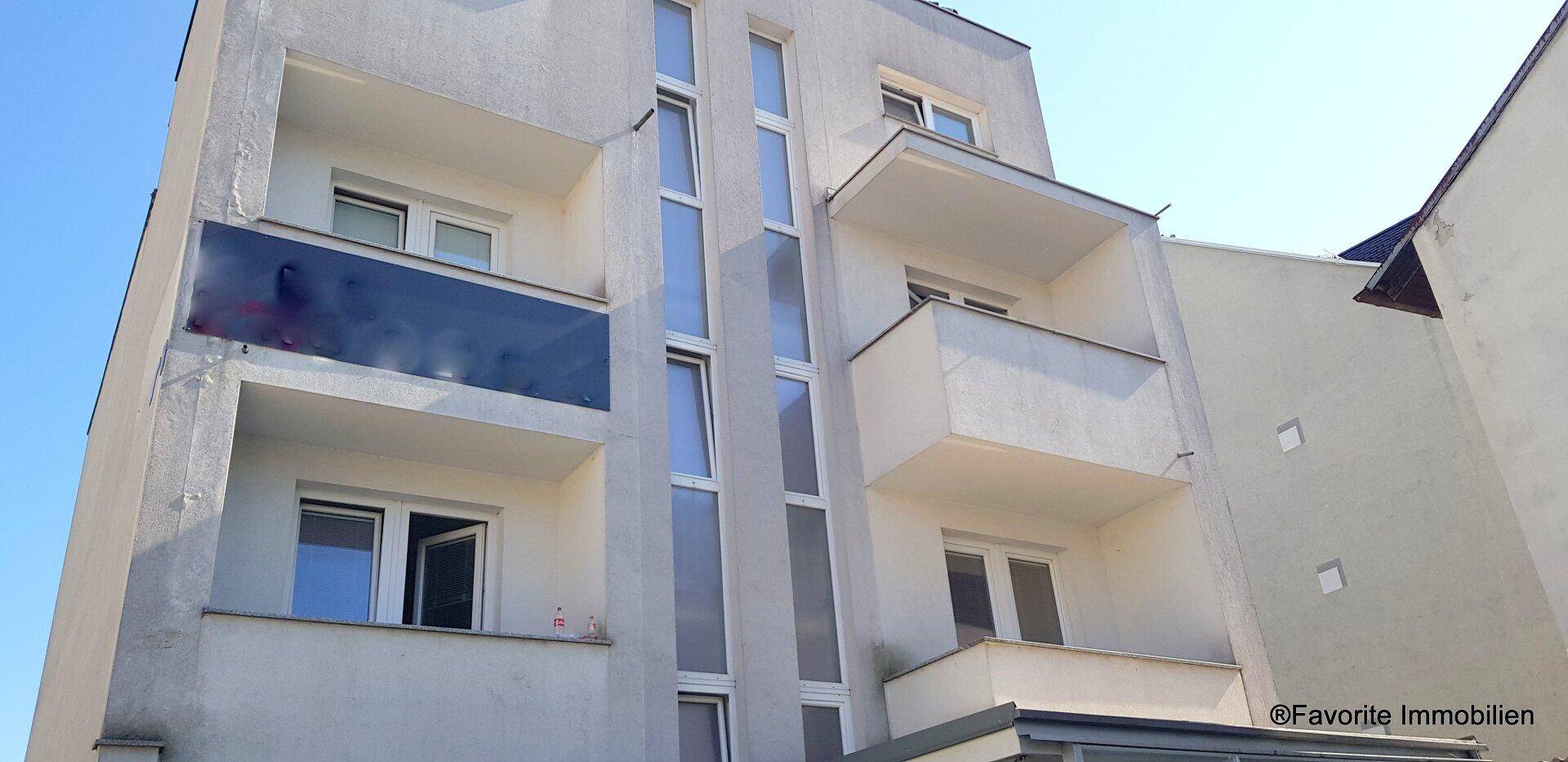 Moderne Gebäudefassade mit Balkonen und vertikalen Fensterbändern, die viel Licht hereinlassen.