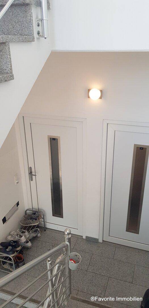Treppenhaus mit Zugangstüren zu den Wohnungen und Fliesenboden, gut beleuchtet.