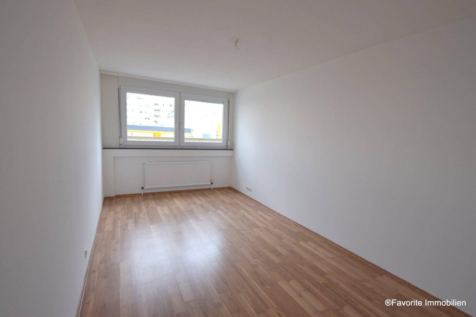 Geräumiges Zimmer mit hellem Laminatboden und Fenster, vielseitig nutzbar als Schlaf- oder Arbeitszimmer.