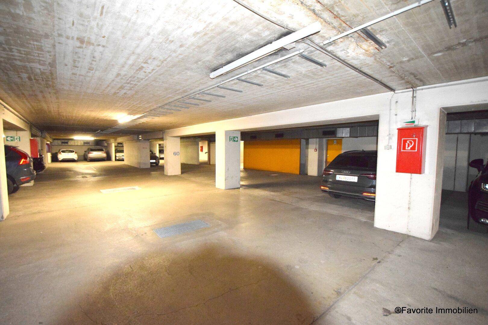Geräumige Tiefgarage mit mehreren Stellplätzen und Betonwänden, gut beleuchtet.