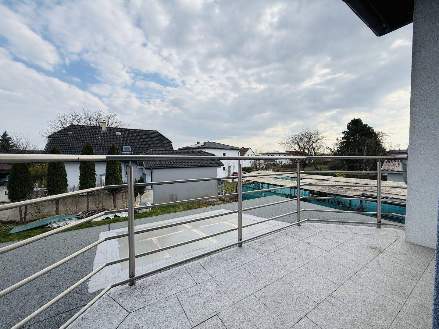 Kleiner Balkon mit Fliesenboden und Metallgeländer, bietet einen Blick auf die Umgebung.