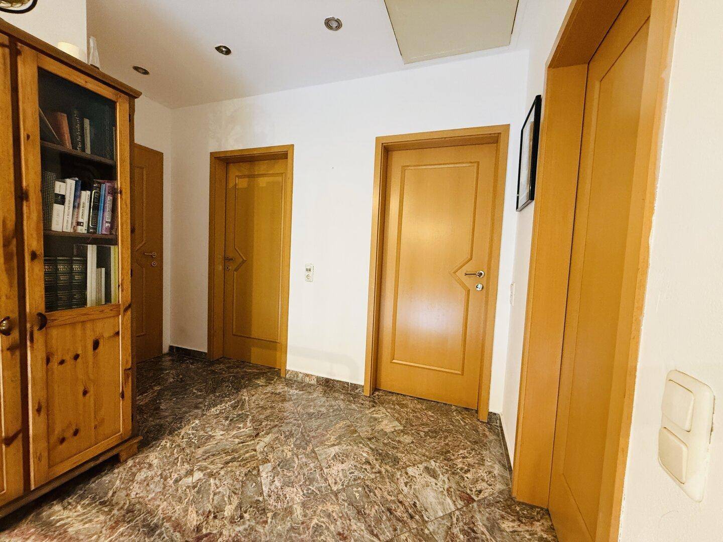 Heller Flur mit Holztüren und Fliesenboden, der zu verschiedenen Räumen führt.