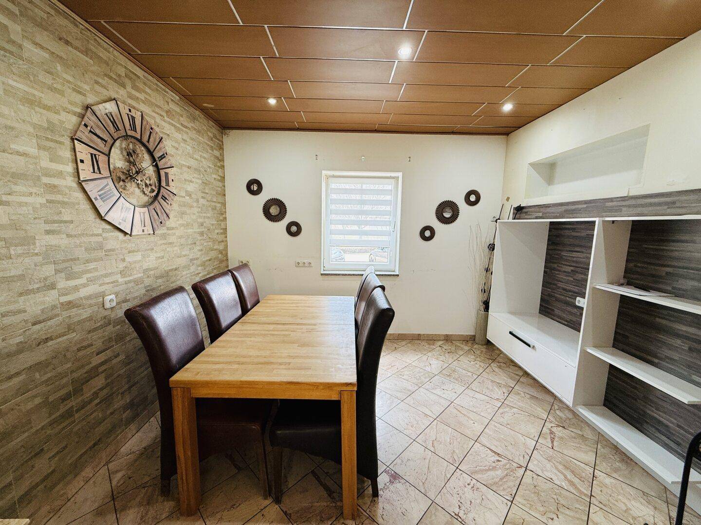 Gemütlicher Essbereich mit Holztisch, Lederstühlen und dekorativer Steinwand, ideal für Familienmahlzeiten.