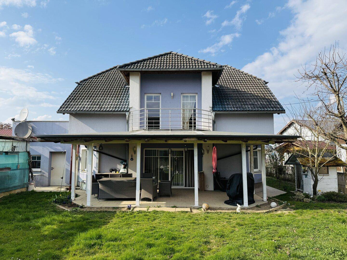 Rückansicht des Hauses mit großem Garten und überdachter Terrasse, ideal für Entspannung im Freien.