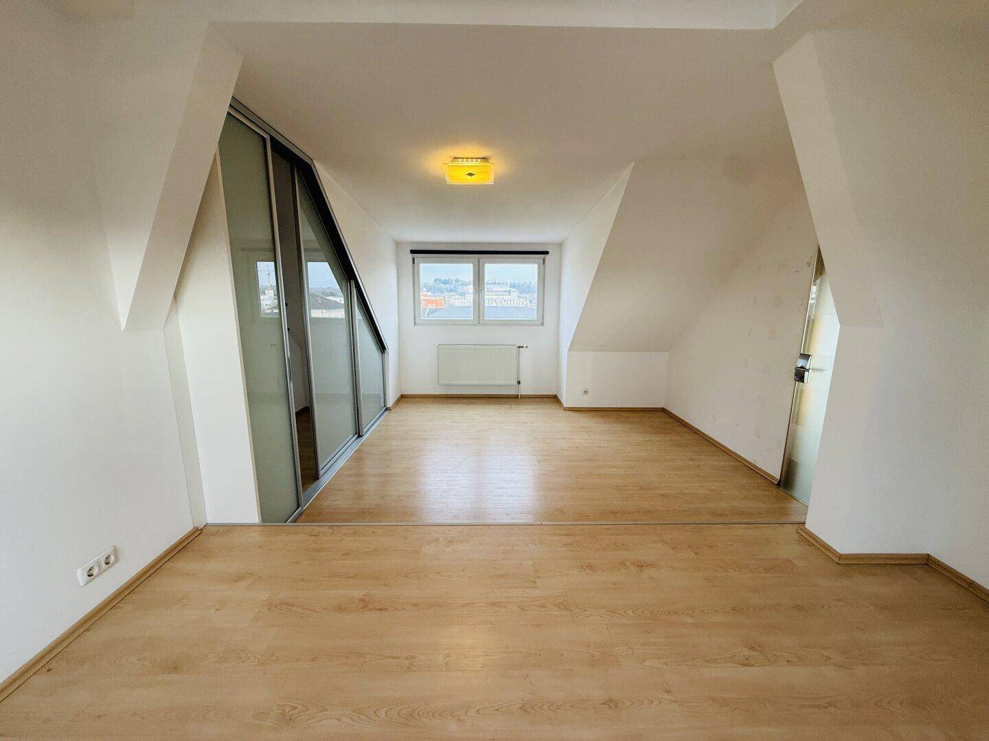 Helles Schlafzimmer mit Laminatboden, Schrägdach und integriertem Schrankbereich.
