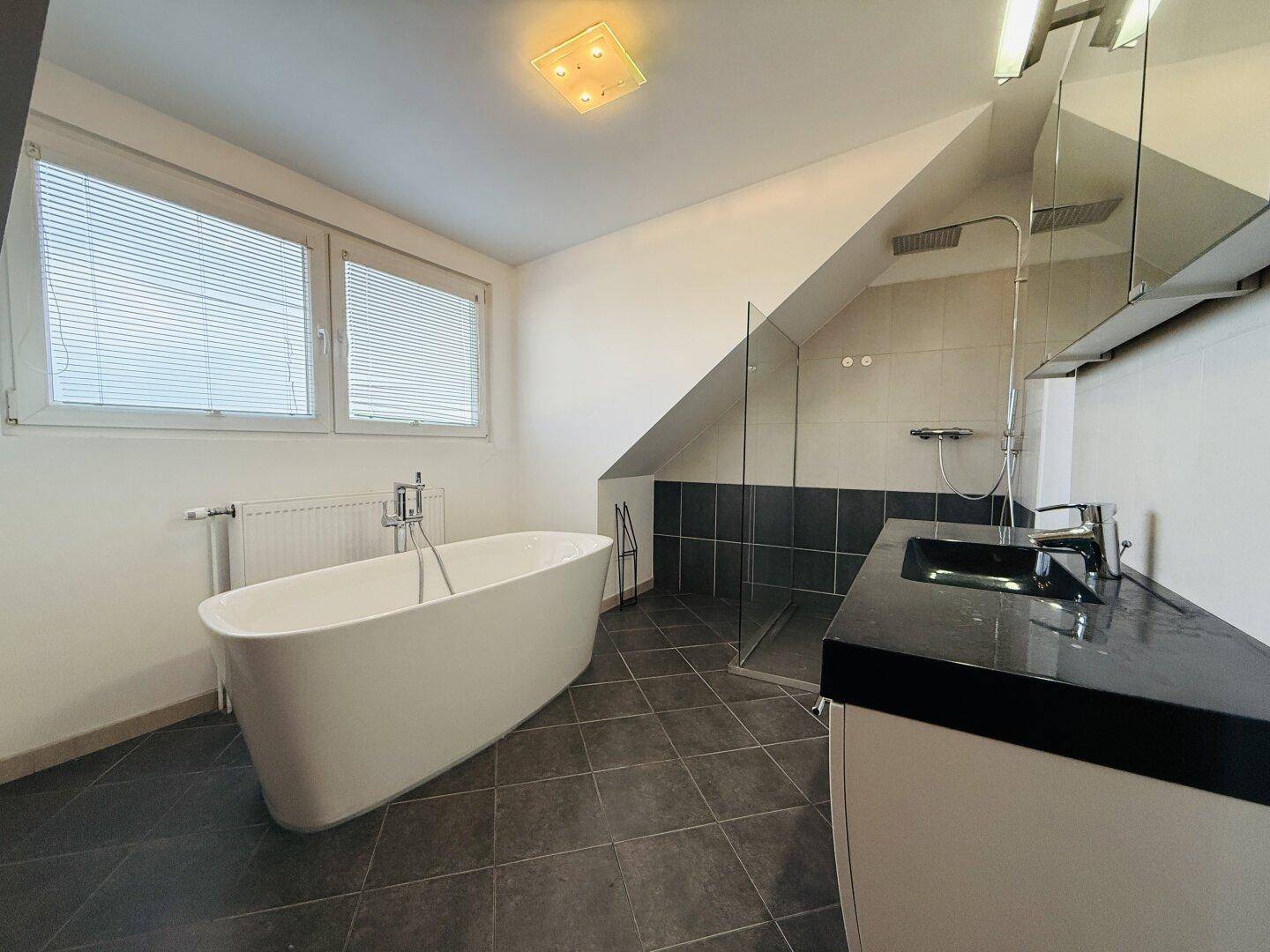 Modernes Badezimmer mit freistehender Badewanne, großer Dusche und Fenster.