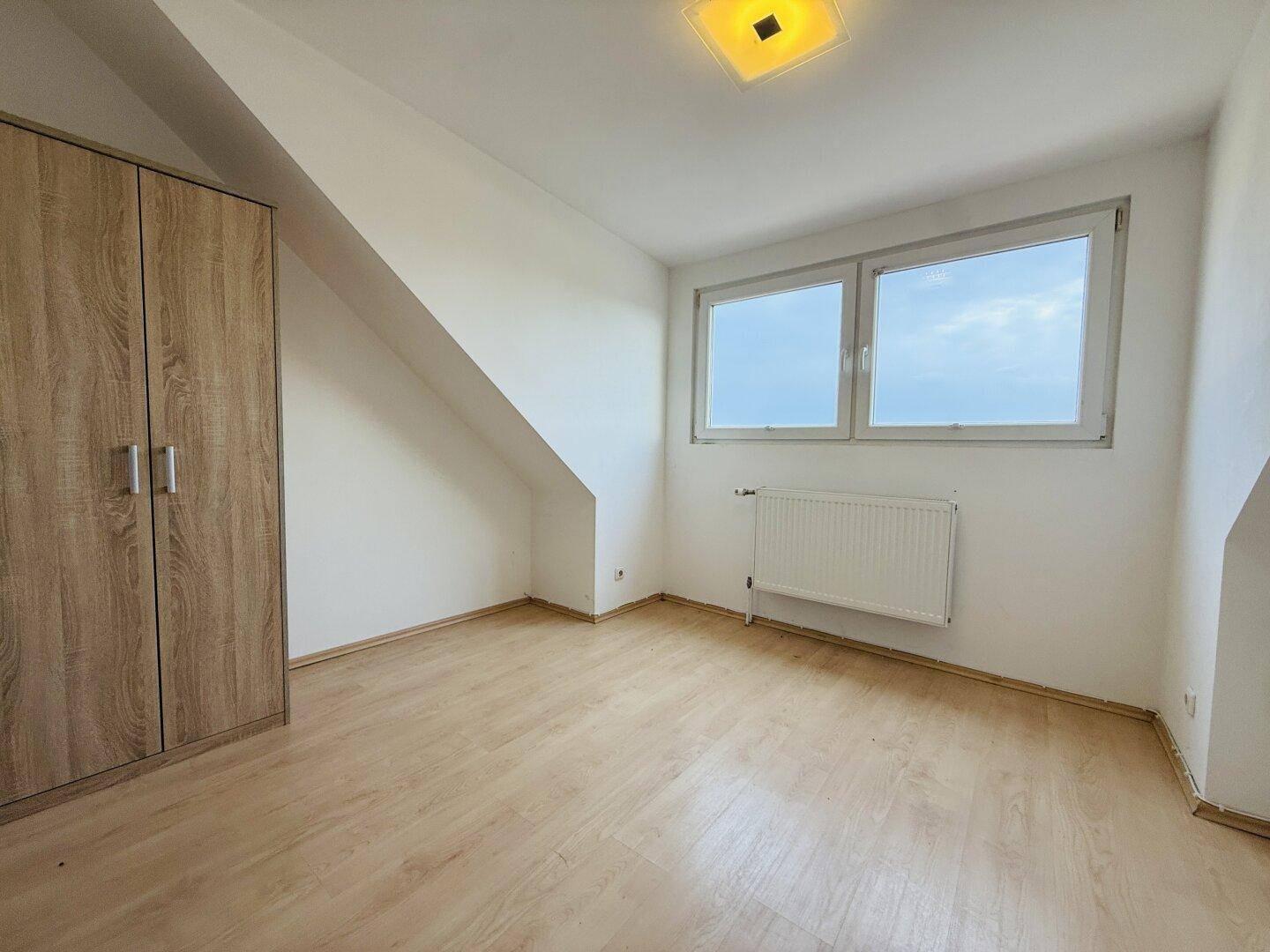 Gemütliches Schlafzimmer im Dachgeschoss mit Laminatboden und Fenster.