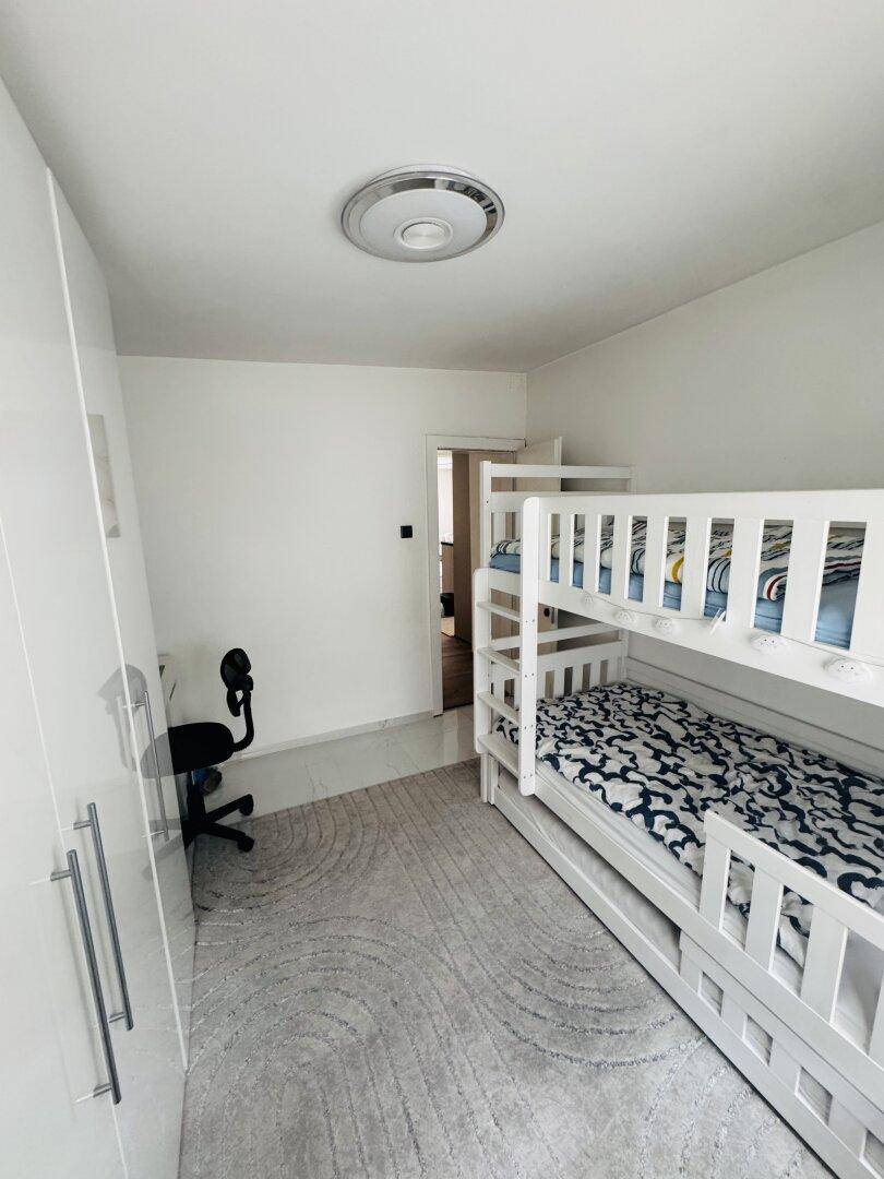 Kinderzimmer mit Etagenbett, Schreibtisch und weißem Kleiderschrank, ideal für Geschwister.