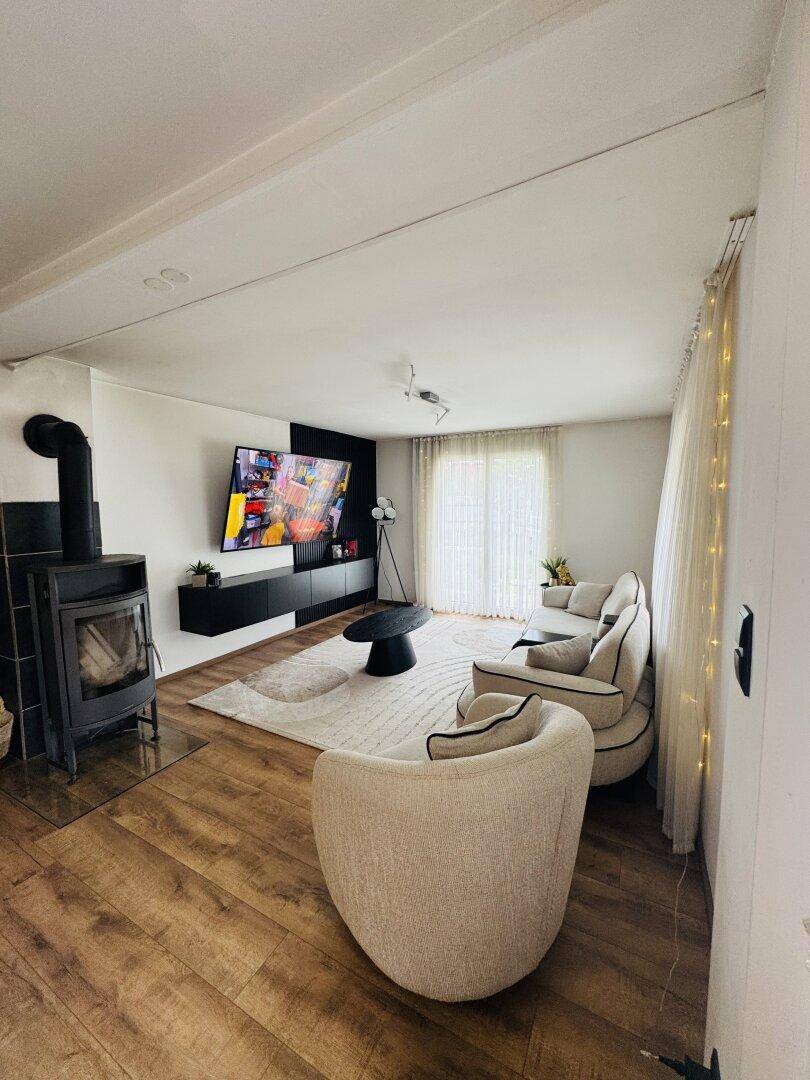 Gemütliches Wohnzimmer mit modernem Kaminofen, bequemen Sofas und Zugang zum Außenbereich.