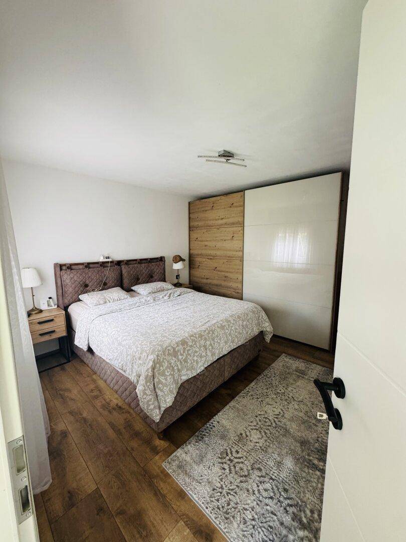 Geräumiges Schlafzimmer mit Doppelbett, Holzboden und integriertem Kleiderschrank.