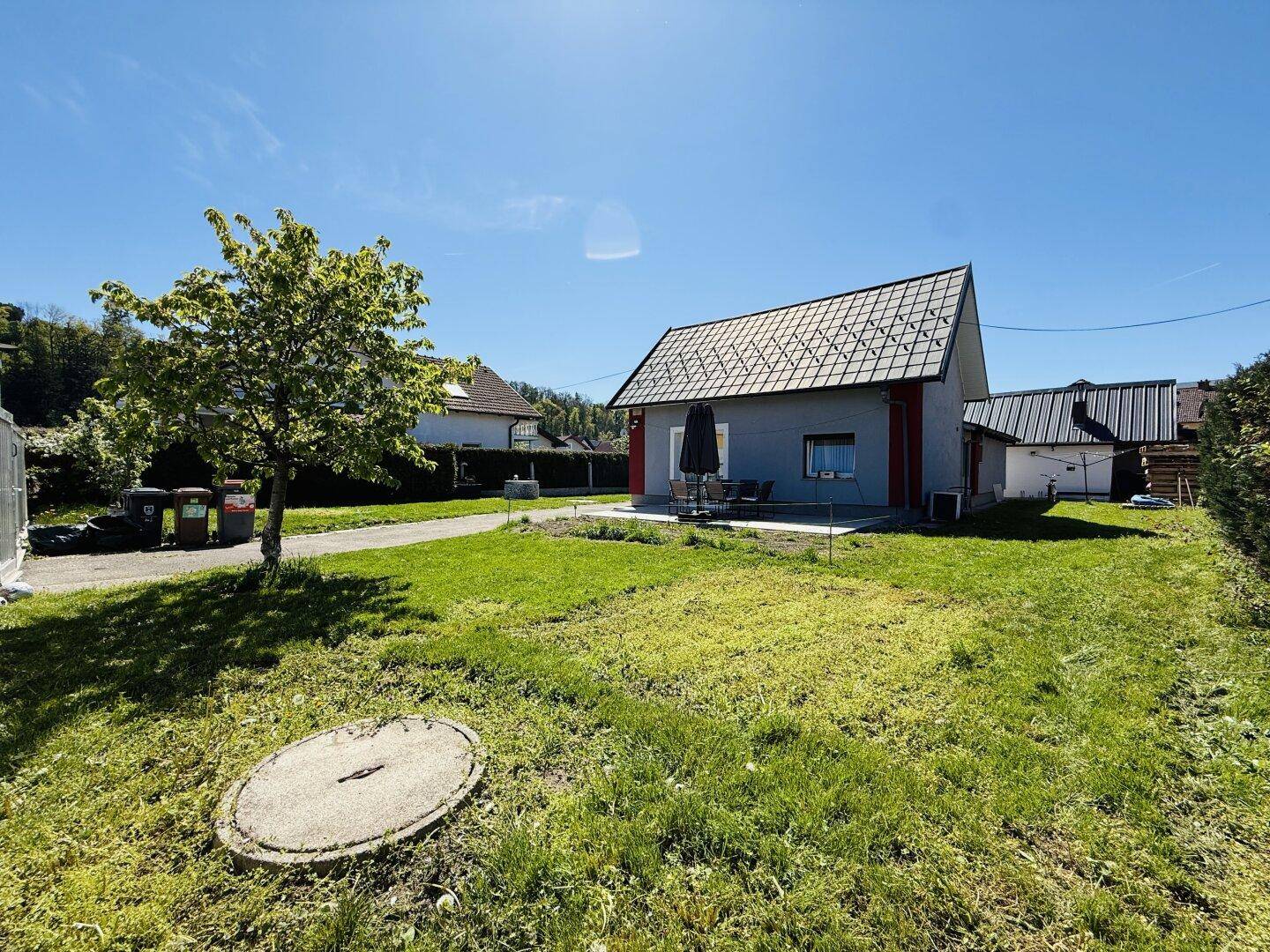 Rückansicht des Hauses mit weitläufigem Rasen und sonnigem Gartenbereich.