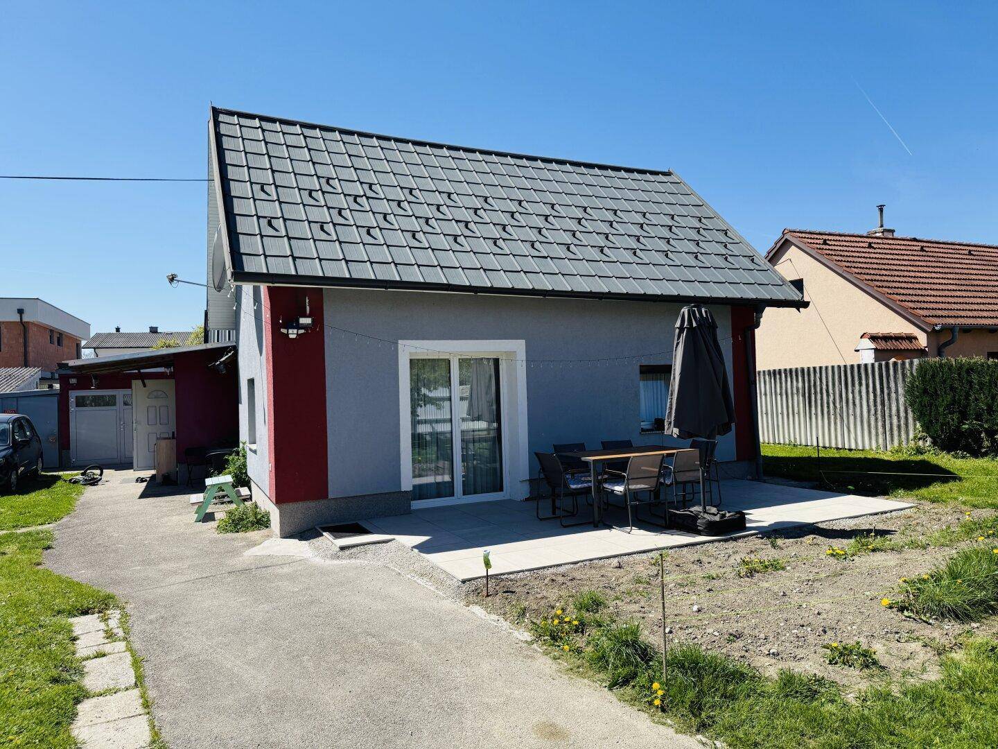Hausansicht mit kleiner Terrasse und gepflastertem Weg, ideal für Mahlzeiten im Freien.