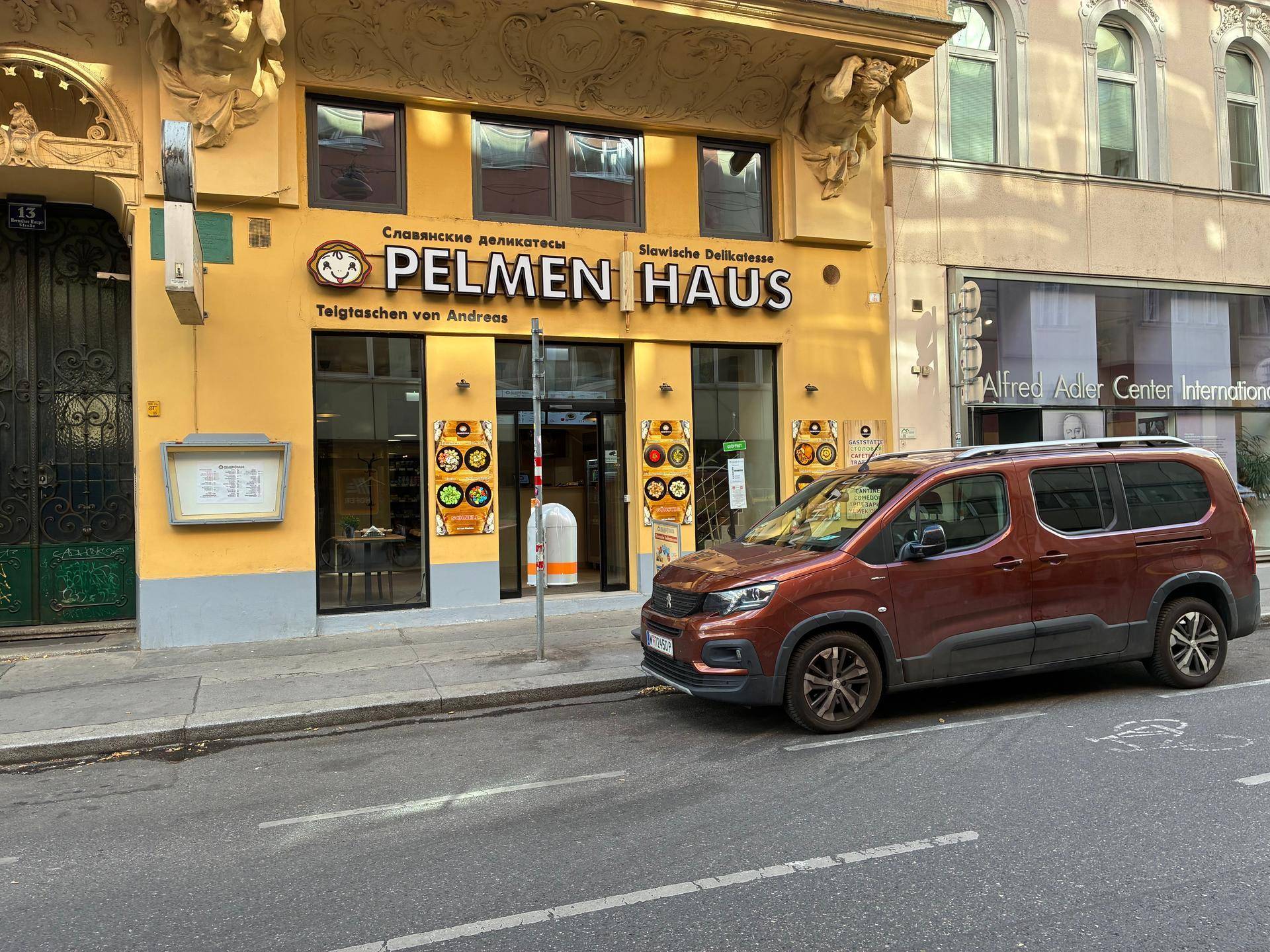 Historische Fassade eines Geschäftsgebäudes mit dem Schild 'Pelmen Haus' und einem geparkten Auto.