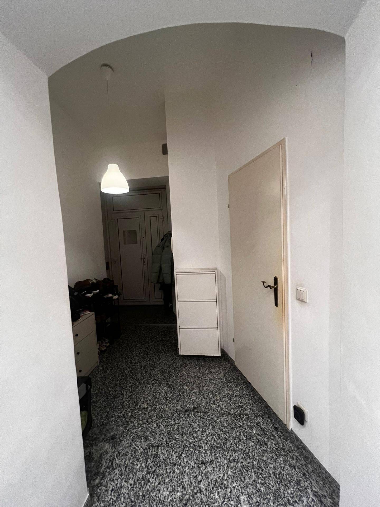 Eingangsbereich mit gefliestem Boden, Schuhschrank und einer Hängelampe.