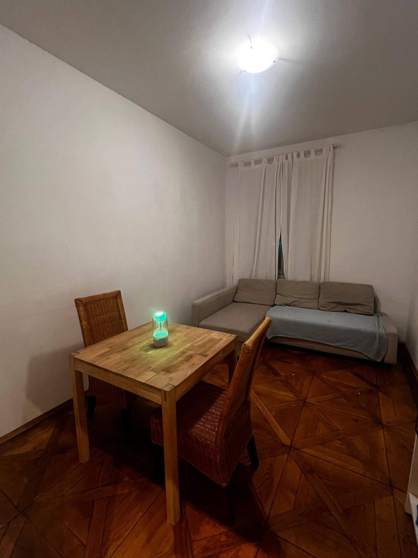 Wohn- und Essbereich mit Holzboden, Esstisch und einem Sofa am Fenster.