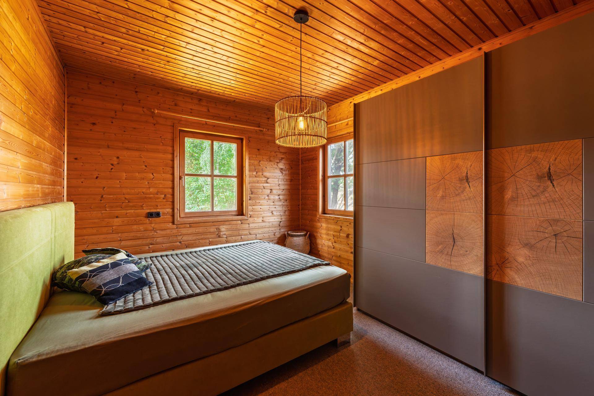 Gemütliches Schlafzimmer mit Holzwänden, Doppelbett und modernem Kleiderschrank.
