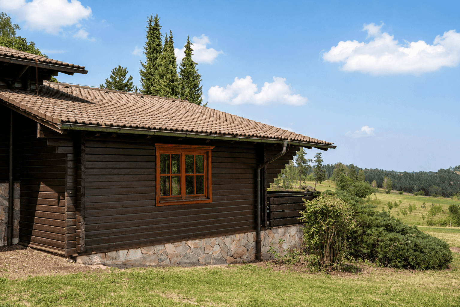 Seitenansicht des Holzchalets mit Ziegeldach und weitem Blick in die Landschaft.