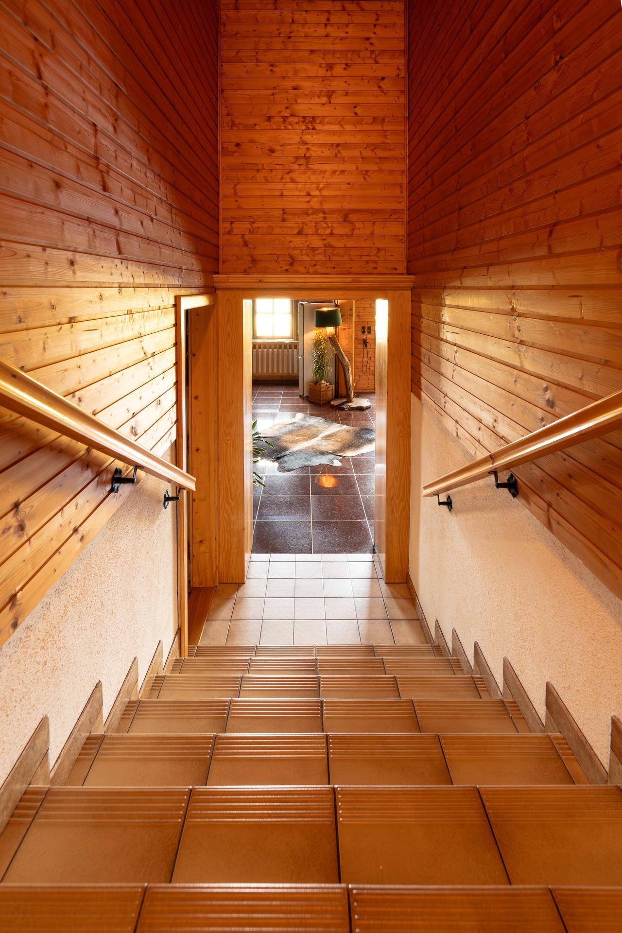 Treppenhaus mit Holzgeländer und Blick auf den Wohnbereich.