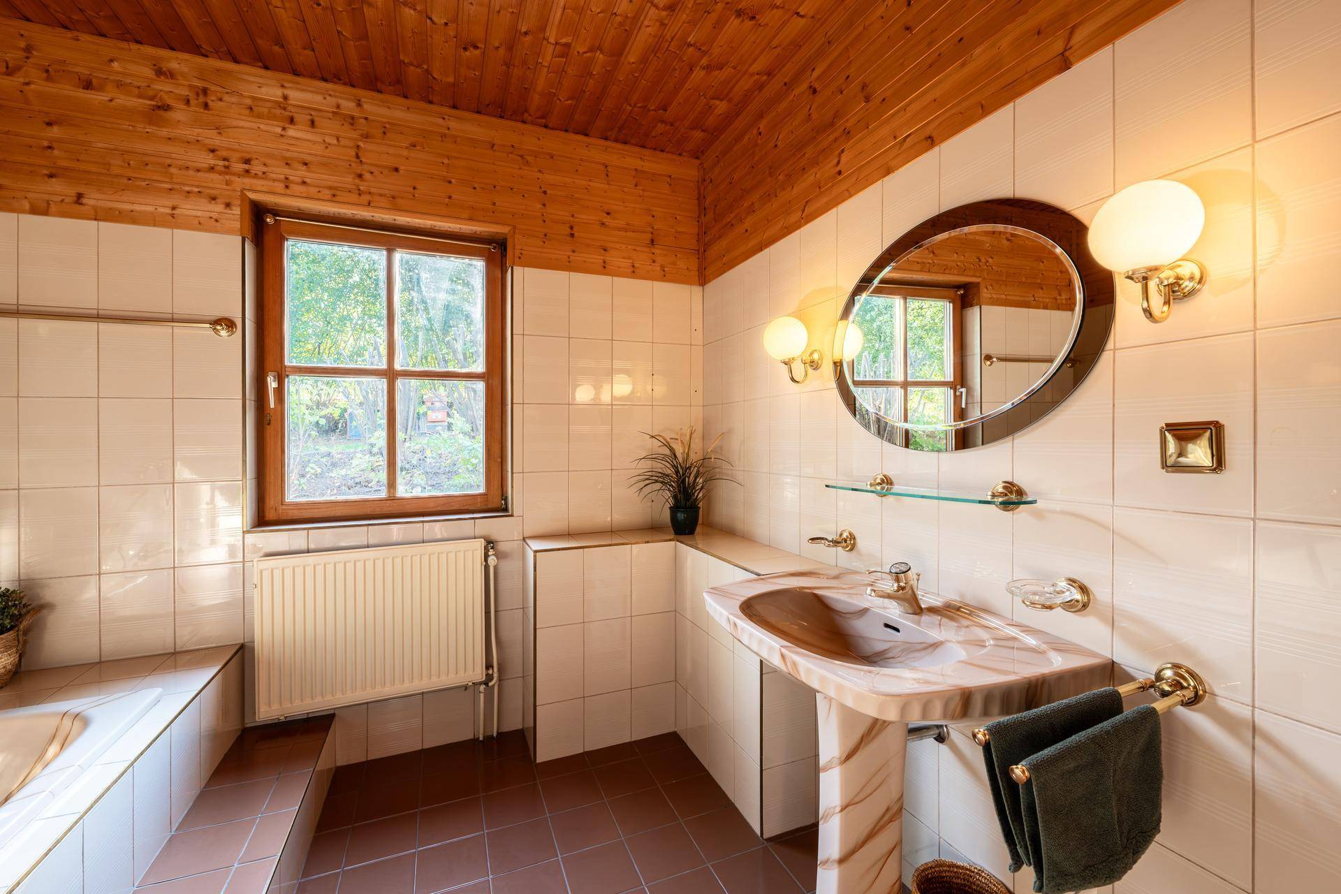 Helles Badezimmer mit Badewanne, Fenster und traditionellen Fliesen.