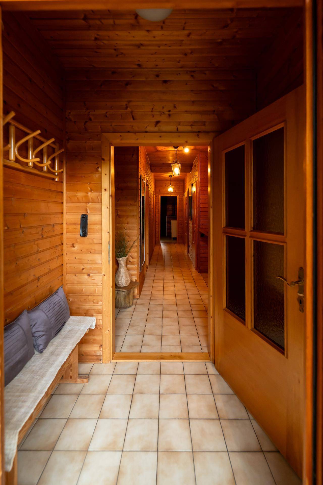 Eingangsbereich mit Holzwänden, gefliestem Boden und Garderobe.