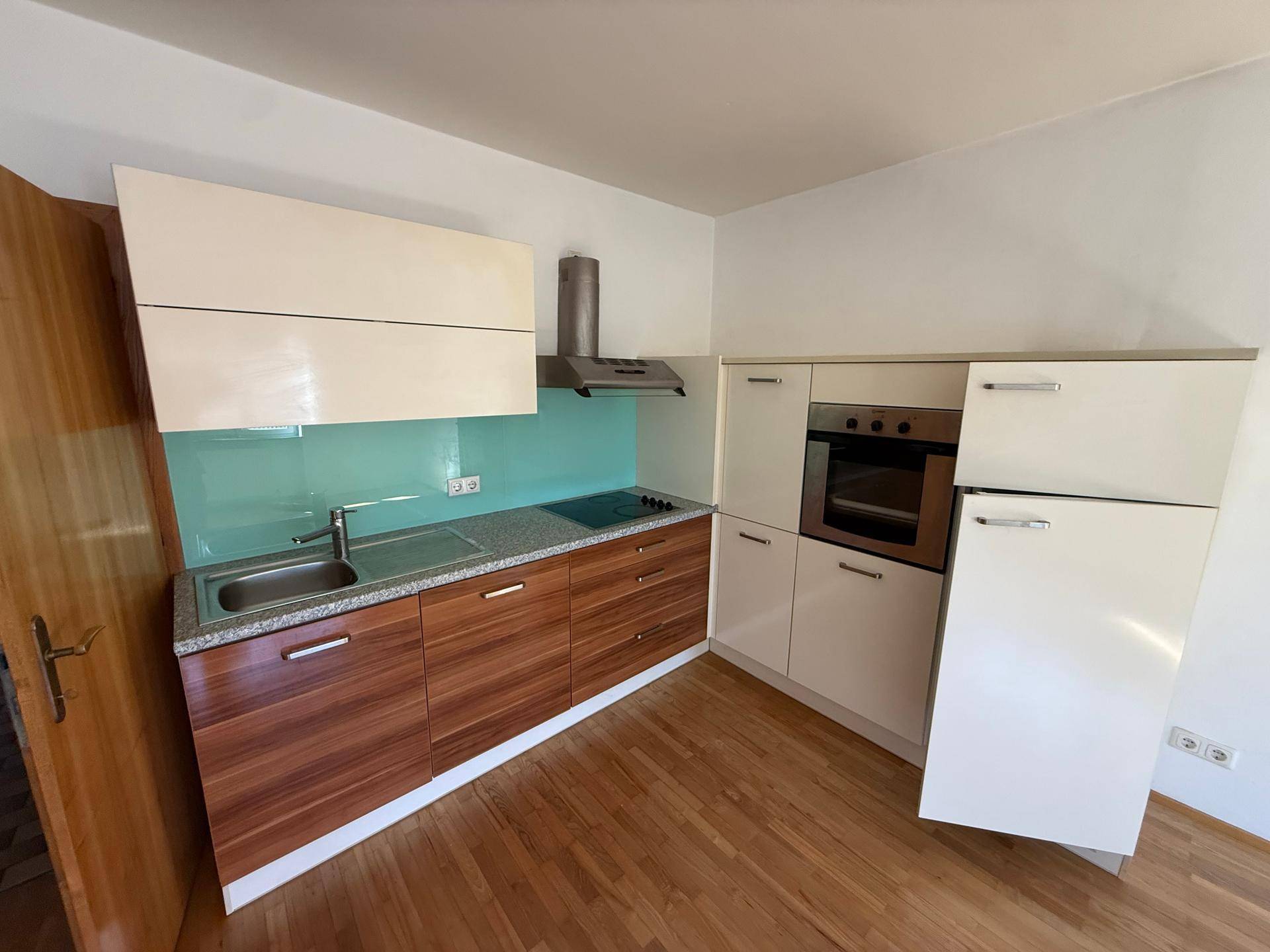 Moderne Küche mit hellen Holz- und weißen Schränken, Induktionskochfeld und integrierten Geräten.