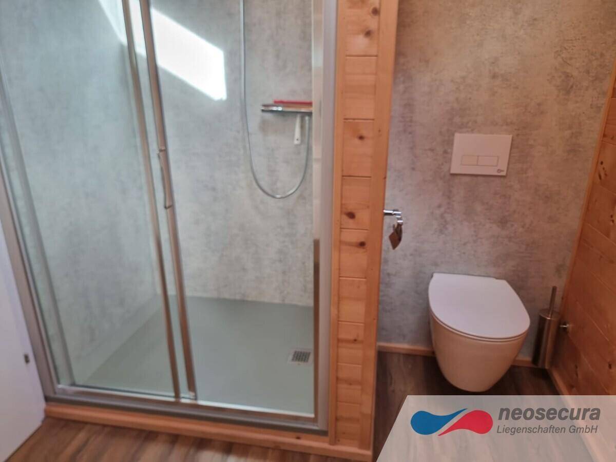 Modernes Badezimmer mit ebenerdiger Dusche, Wand-WC und Holzelementen, funktional und hell gestaltet.