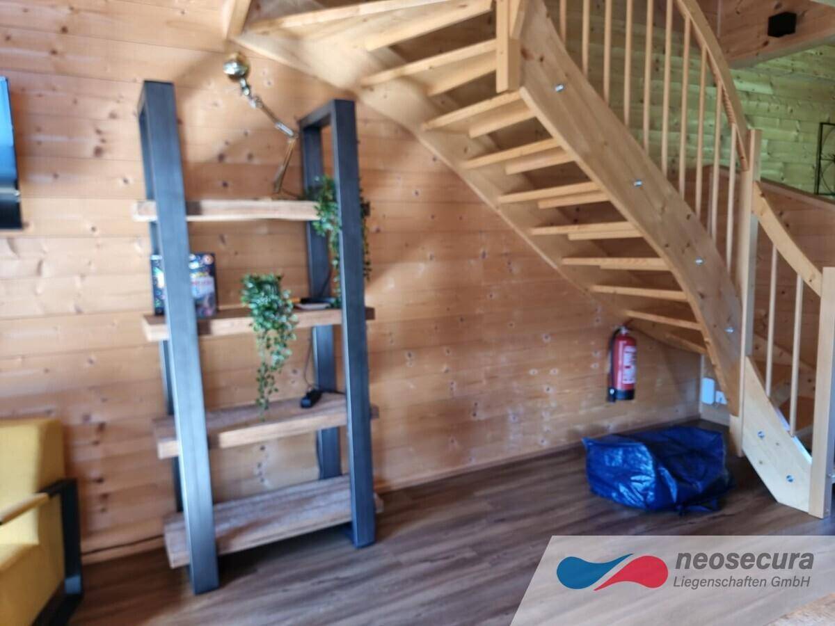 Offener Wohnbereich mit Holztreppe und modernem Regal, schafft eine warme und einladende Atmosphäre.