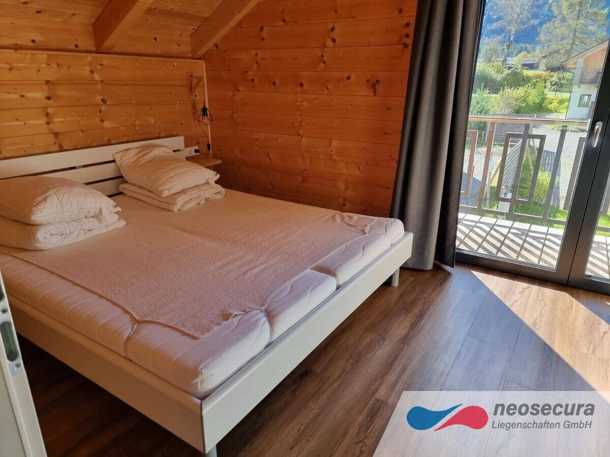 Schlafzimmer mit Doppelbett und direktem Zugang zum Balkon, lichtdurchflutet und einladend.