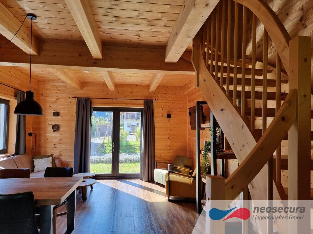 Heller Wohnbereich mit Holztreppe, großen Fenstern und Blick ins Grüne, offen und lichtdurchflutet.