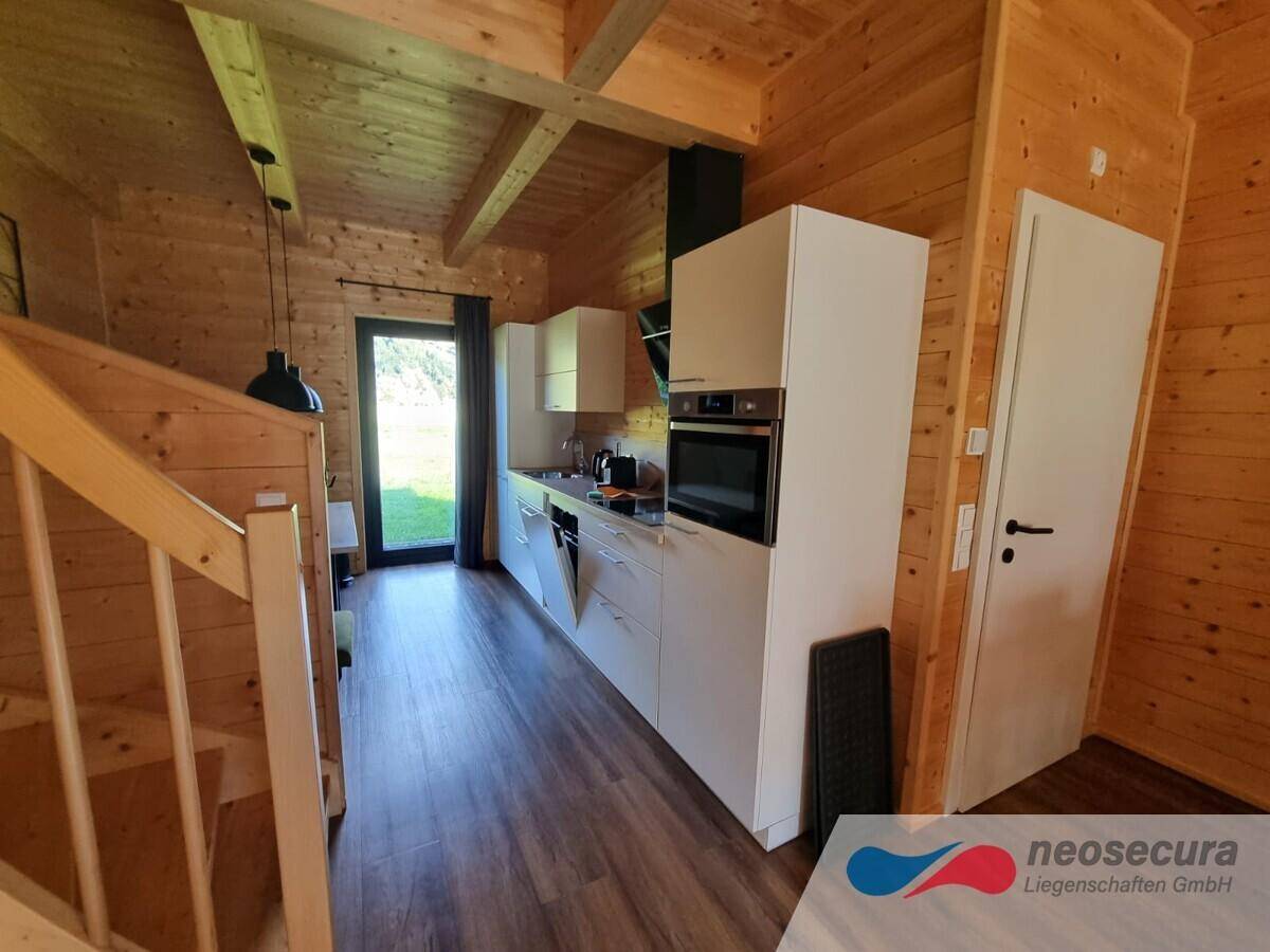 Funktionale Küche mit weißen Schränken, modernen Geräten und direktem Zugang zum Gartenbereich.