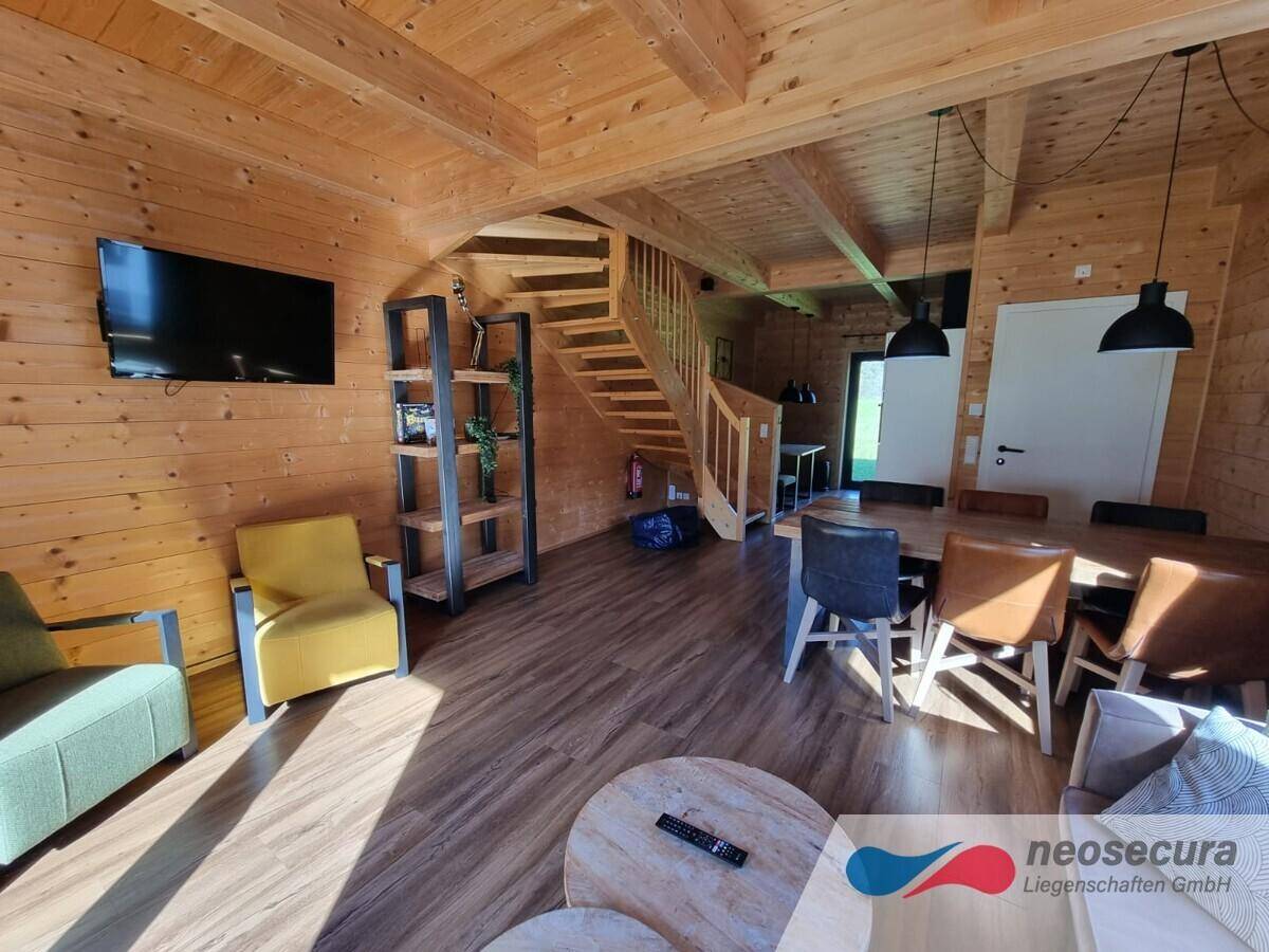 Geräumiger offener Wohn- und Essbereich mit Holzelementen, Fernseher und gemütlichen Sitzgelegenheiten.