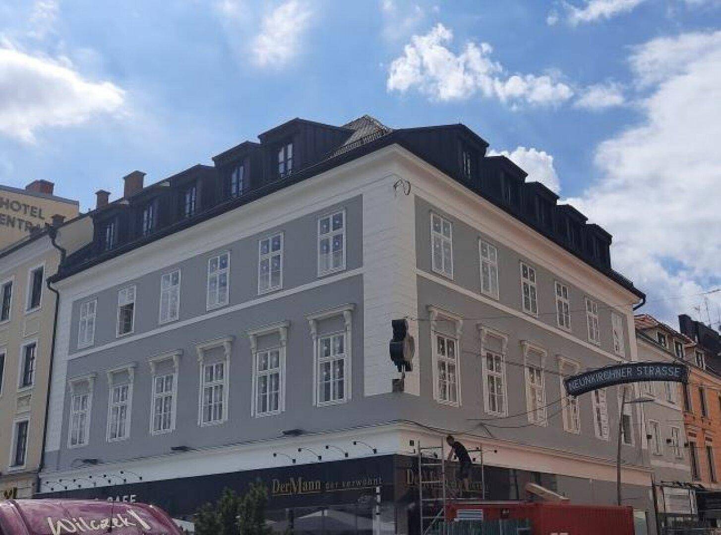 Historisches Gebäude mit modernisierter Fassade und vielen Fenstern in einer städtischen Umgebung.
