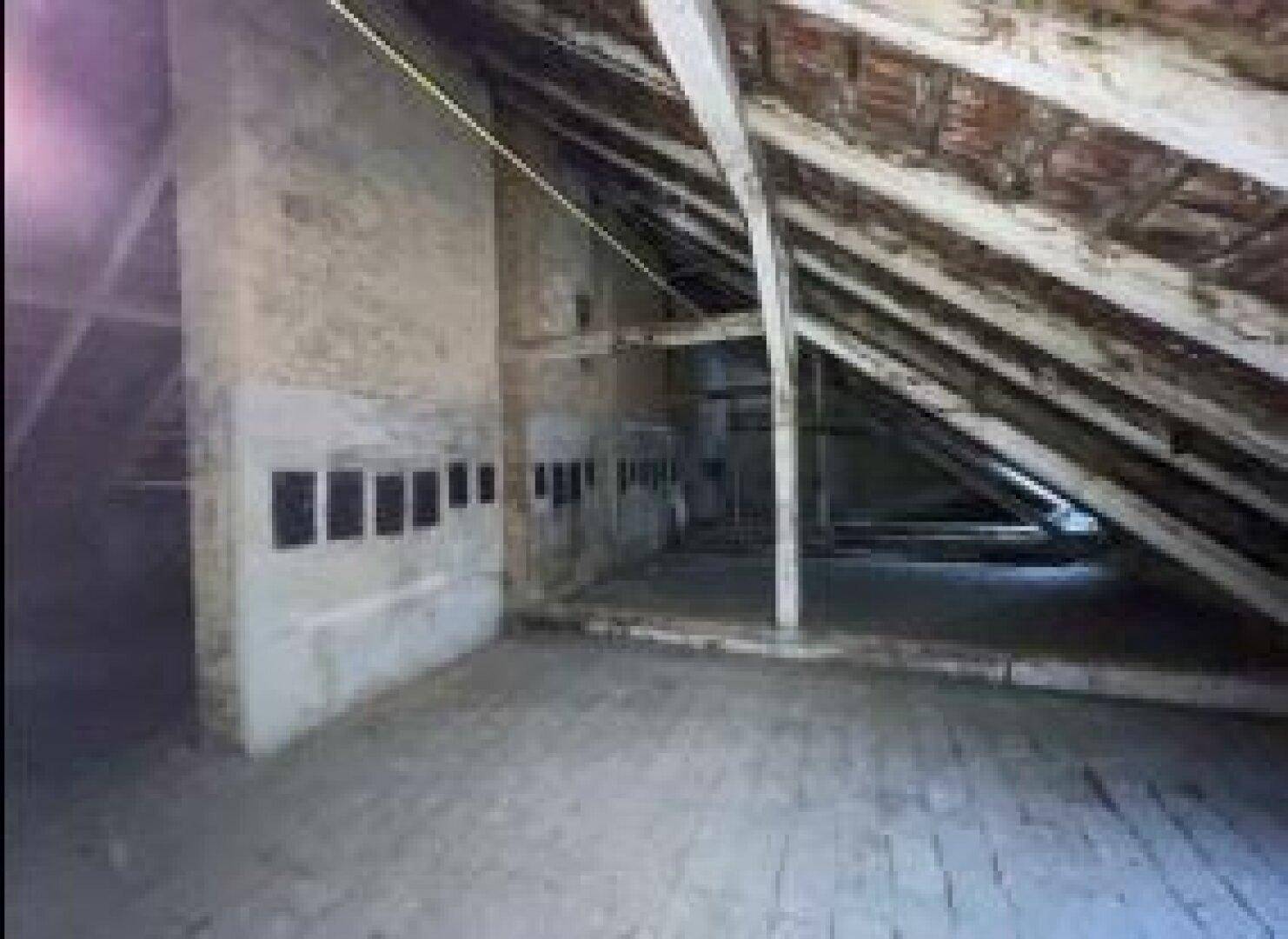 Unausgebauter Dachboden mit schrägen Wänden und Holzbalken, bietet viel Potenzial für zukünftige Nutzung.