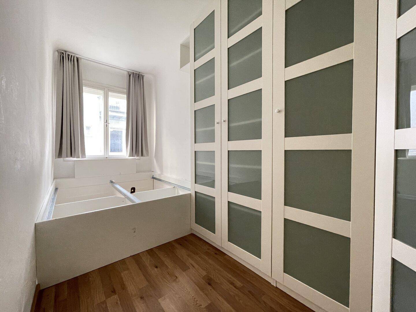 Schlafzimmer mit Einbauschränken und einem Bettgestell, das viel Stauraum bietet.