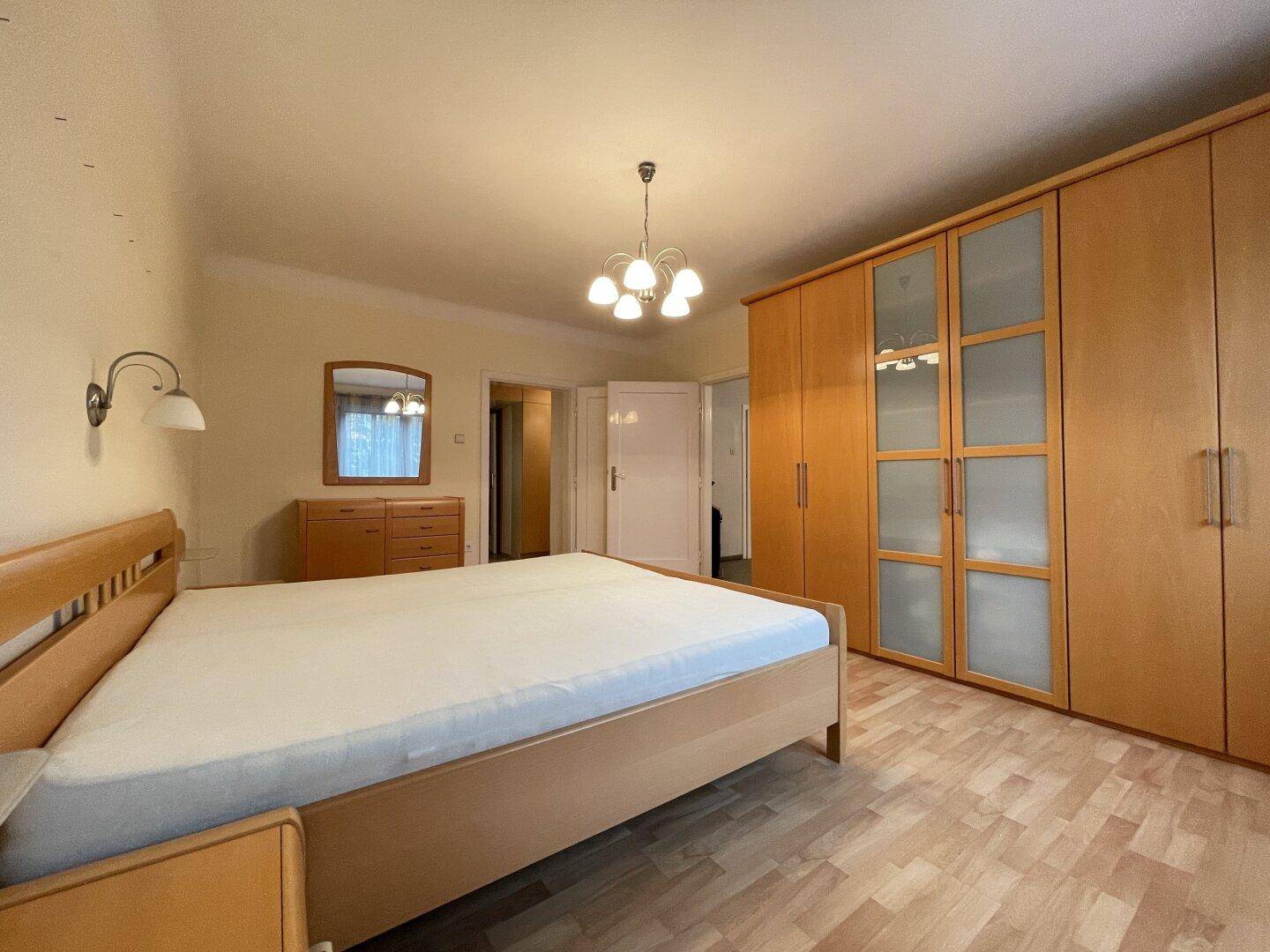 Geräumiges Schlafzimmer mit Doppelbett, großen Holzschränken und Laminatboden.