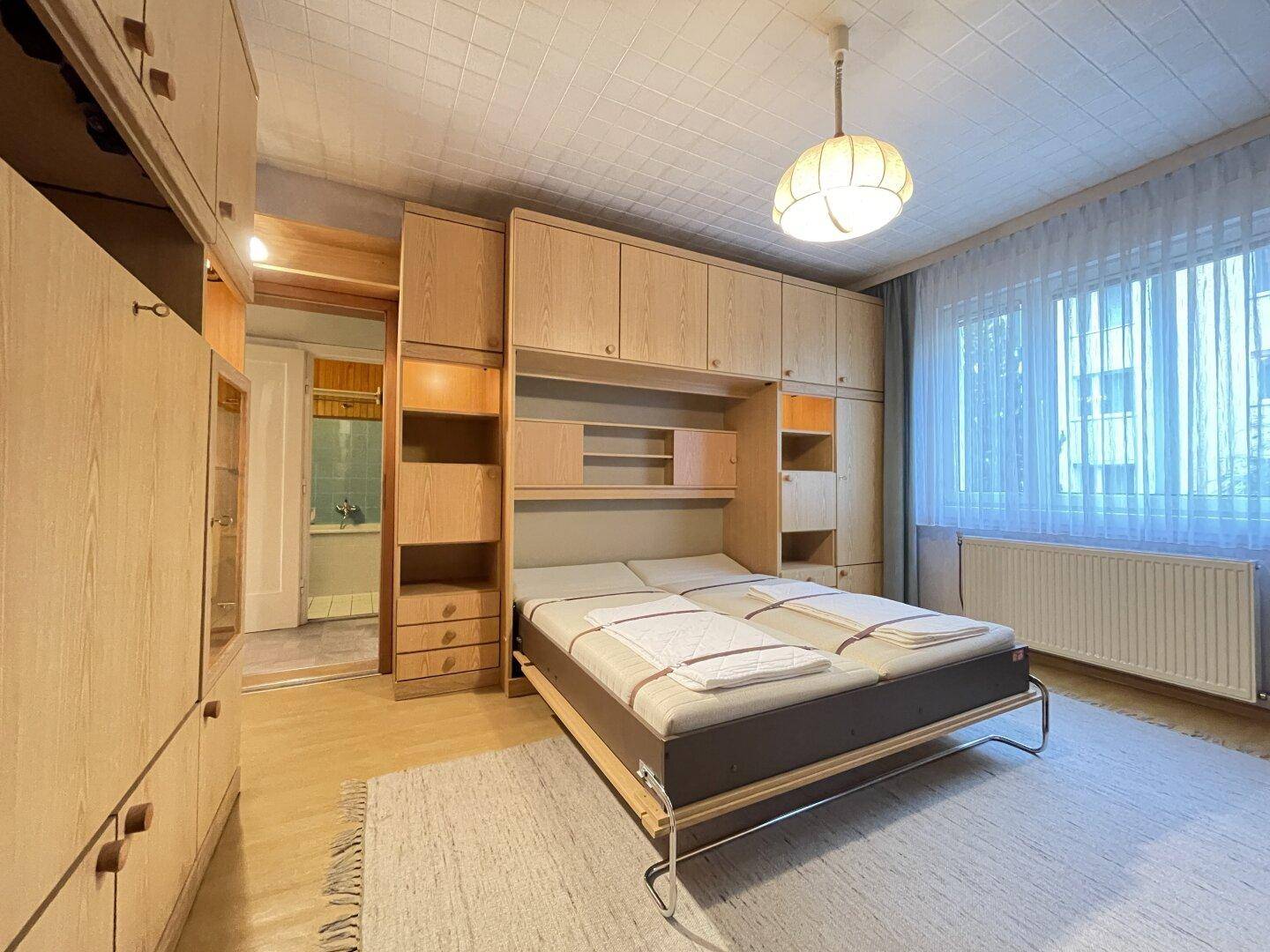 Schlafzimmer mit Einzelbetten, Einbauschränken und hellem Holzdekor.