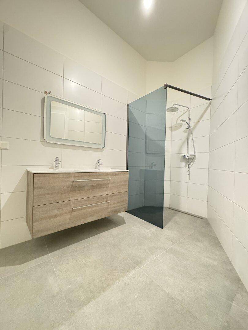 Modernes Badezimmer mit Doppelwaschbecken, schwebendem Waschtisch und begehbarer Dusche.