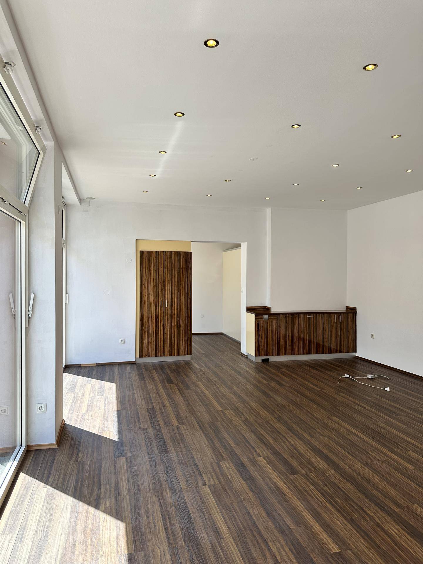 Großer, heller Geschäftsraum mit dunklem Holzboden und Einbaustrahlern in der Decke, bereit zur Nutzung.