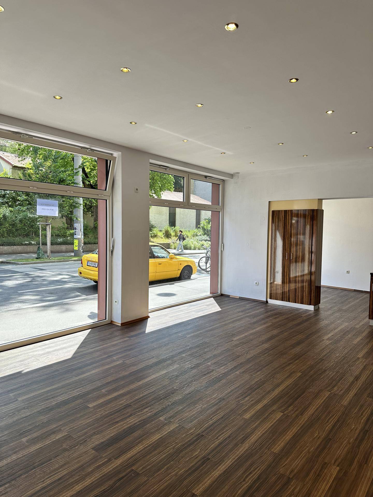 Heller, leerer Geschäftsraum mit großen Schaufenstern und dunklem Holzboden, ideal für ein Geschäft.