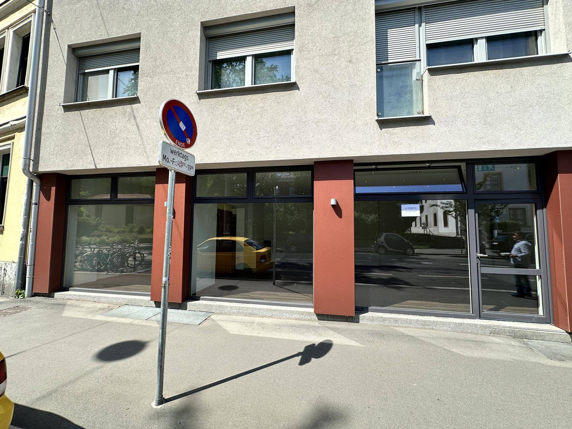 Nahaufnahme der Ladenfront eines Gebäudes mit großen Schaufenstern und einem Verkehrsschild.