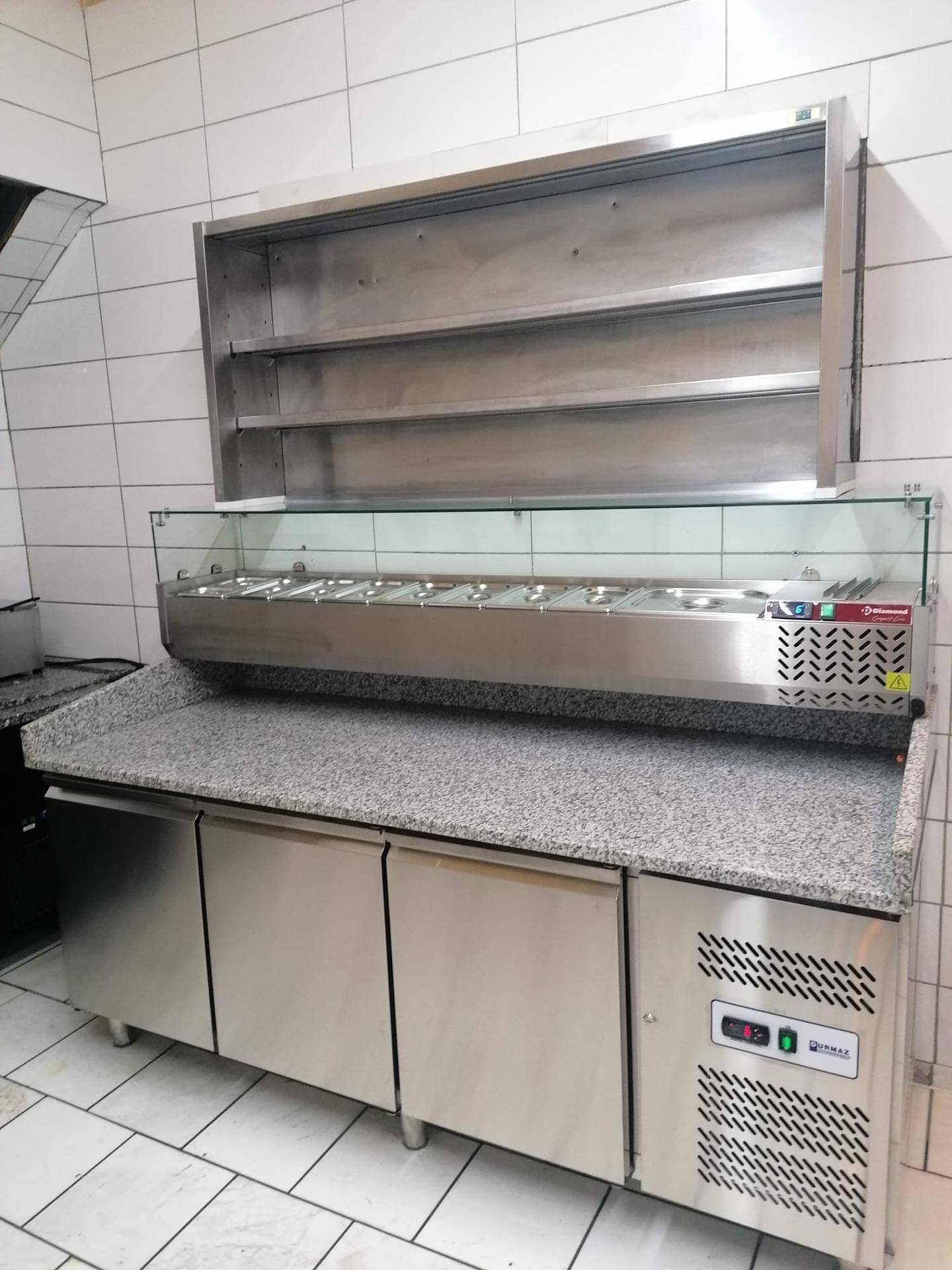 Vorbereitungsbereich einer Gewerbeküche mit Granitarbeitsplatte und Kühltheke.