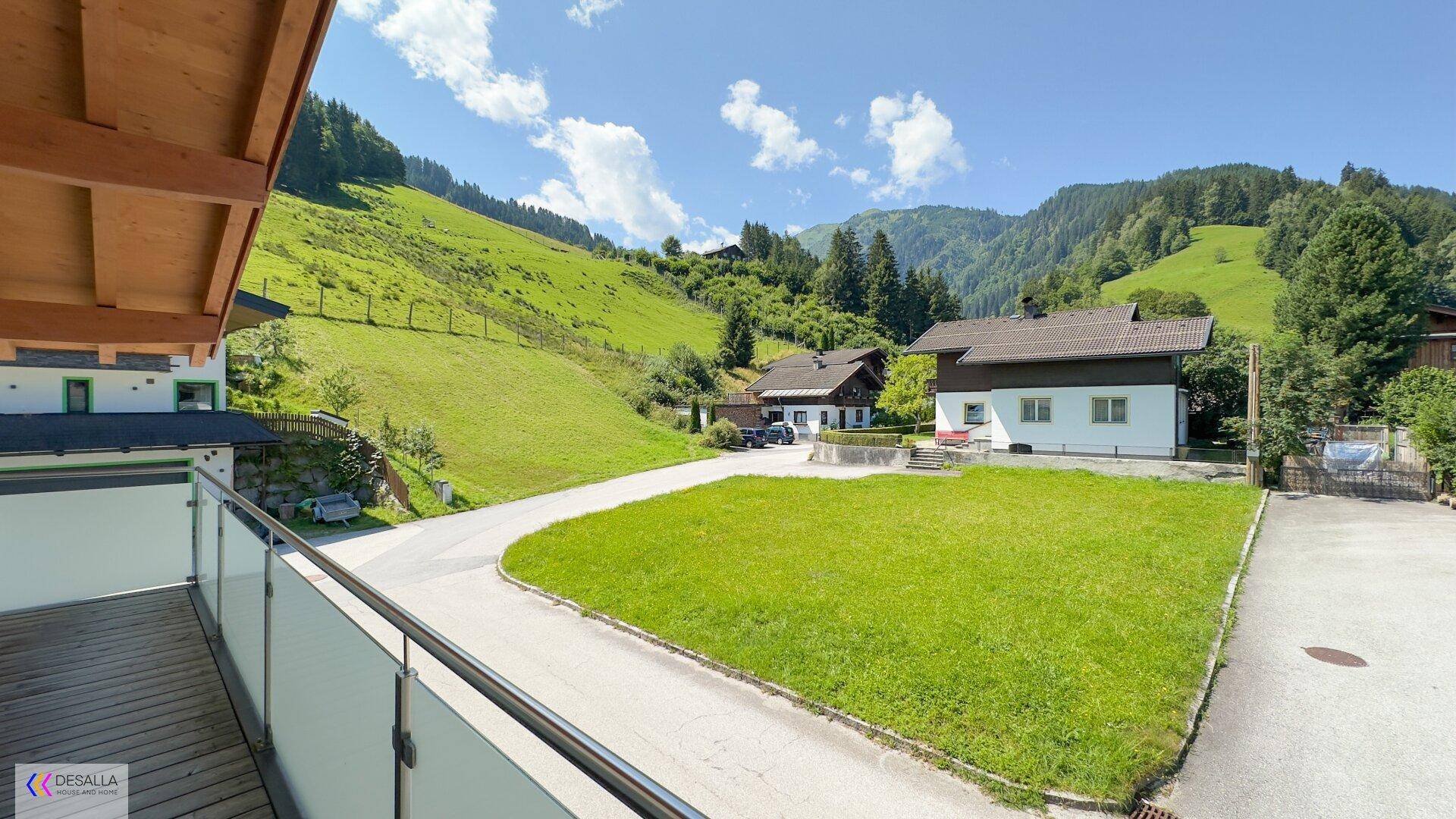 Balkon mit Glasbrüstung bietet einen weiten Blick auf die grüne Berglandschaft.