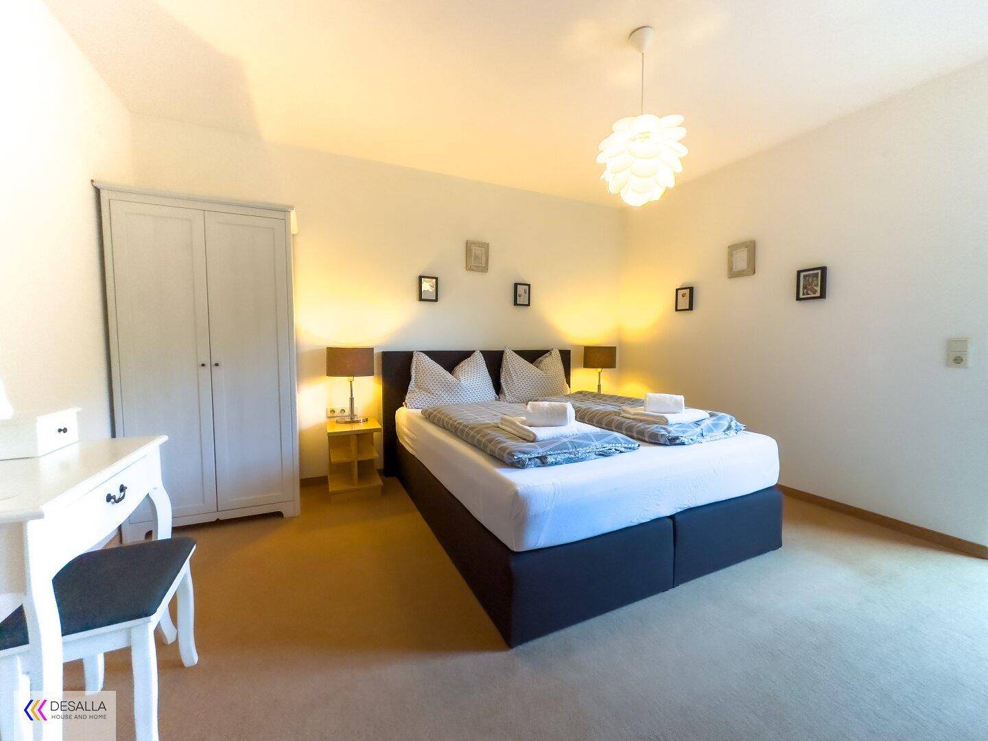 Helles Schlafzimmer mit Doppelbett, Teppichboden und schlichtem, modernem Dekor.