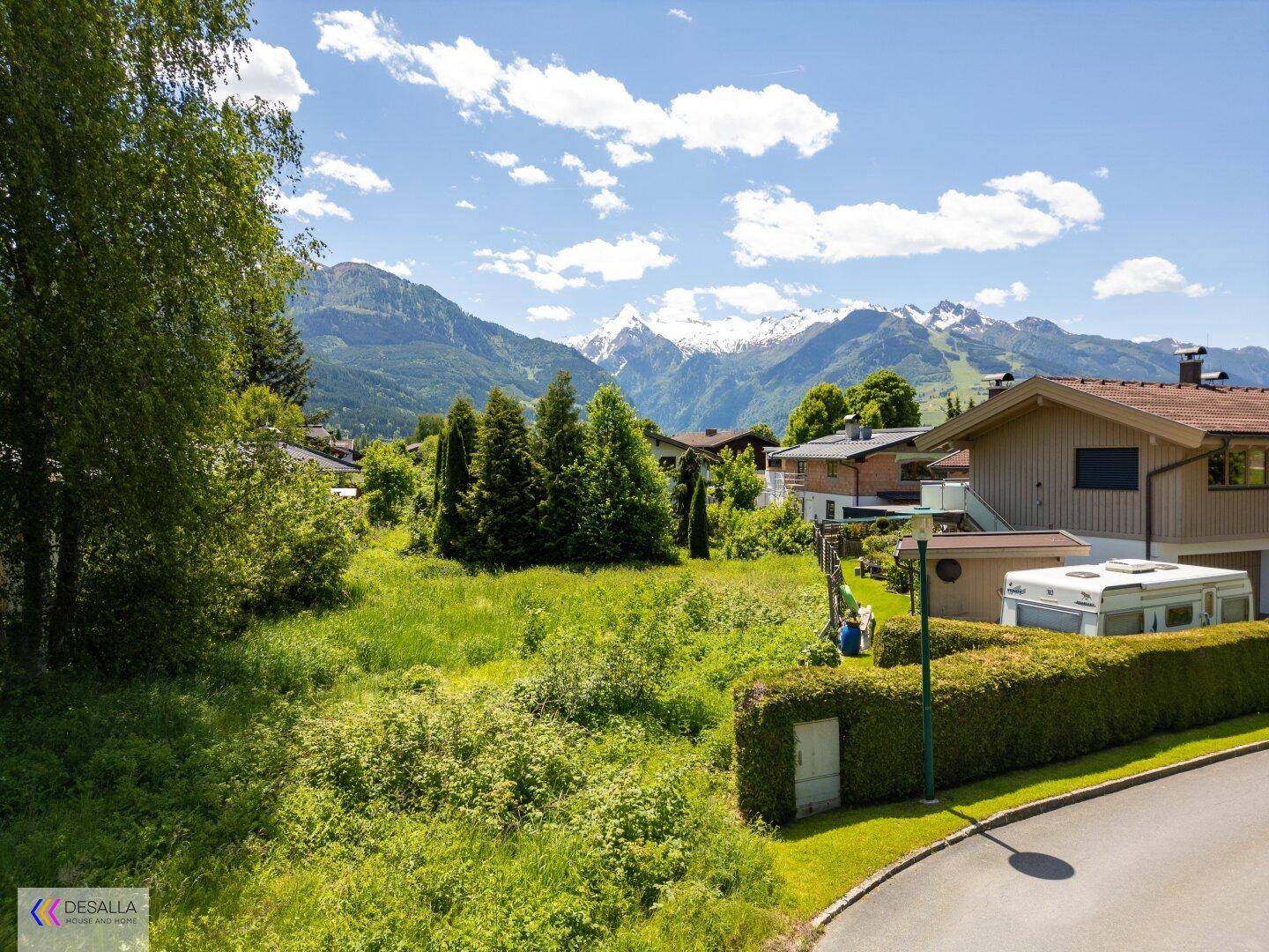 Grünes Baugrundstück mit beeindruckendem Blick auf die schneebedeckten Berge im Hintergrund.