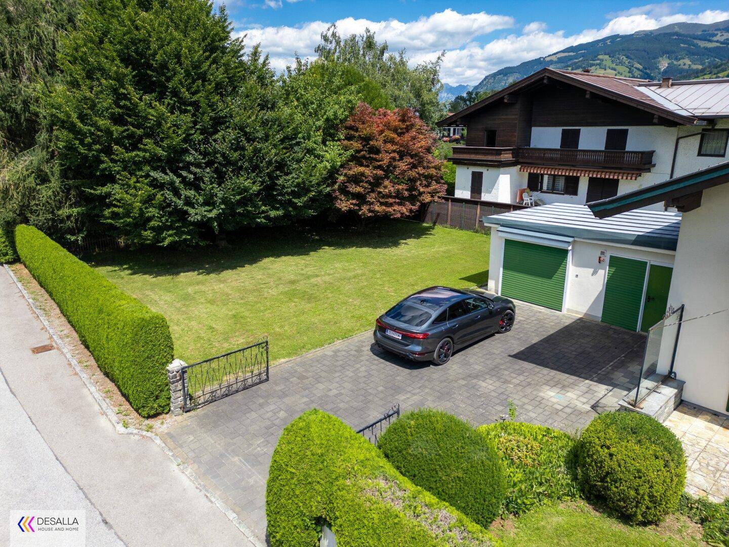 Vorderansicht des Hauses mit gepflasterter Auffahrt, Garage und einem grünen Vorgarten.